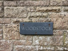 A stone wall with a rectangular metal plaque reading Woodstock at Woodstock in Chaffcombe near Chard