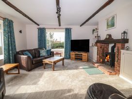 A living room with a leather sofa wooden coffee table television and fireplace at Woodstock in Chaffcombe near Chard