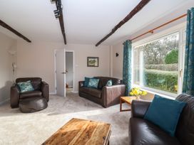 A living room with leather sofas wooden coffee table and a large window with blue patterned curtains at Woodstock in Chaffcombe near Chard