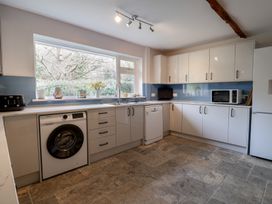 A kitchen with white cabinets a washing machine dishwasher microwave toaster and refrigerator at Woodstock in Chaffcombe near Chard