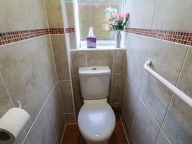 A small bathroom with a toilet a window a tissue box a vase with flowers a toilet brush and a towel rail at Woodstock in Chaffcombe near Chard