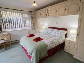 A bedroom with a bed with floral bedding and red towels on top with bedside tables and lamps at Woodstock in Chaffcombe near Chard