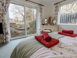 A bedroom with a bed and red towels near a window and a dressing table at Woodstock in Chaffcombe near Chard