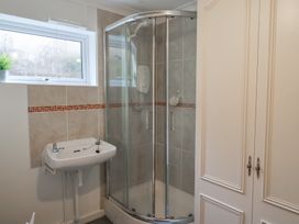 A bathroom with a corner shower enclosure a wall-mounted sink and a window at Woodstock in Chaffcombe near Chard