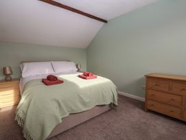 A bedroom with a bed, bedside tables with lamps and a wooden chest of drawers at Woodstock in Chaffcombe near Chard