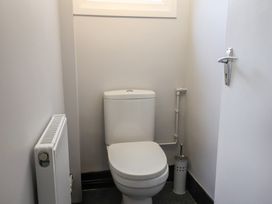 A small bathroom with a white toilet a toilet brush holder a radiator and a window at Woodstock in Chaffcombe near Chard
