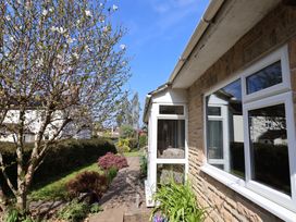A garden path alongside a stone house with windows and flowering tree at Woodstock in Chaffcombe near Chard