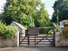 A gate leading to a driveway with a shed and trees at Woodstock in Chard