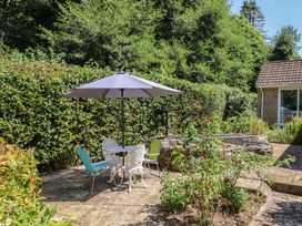 A garden with a table and chairs under an umbrella at Woodstock in Chard