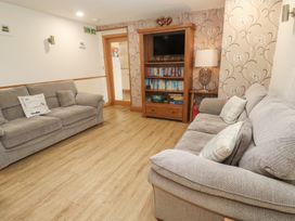 A living room with sofas and a bookshelf at Ash Barn in Falmouth