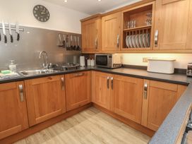 A kitchen with wooden cabinets and a stainless steel sink at Ash Barn in Falmouth