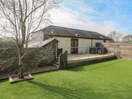 A garden with a deck and tree at Ash Barn in Falmouth