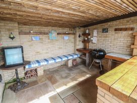A room with a television, bench and grill at Ash Barn in Falmouth