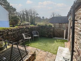 A garden area with chairs and a stone wall at Ash Barn in Falmouth