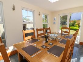A dining room with a wooden table set for six with placemats glasses cutlery and a bottle at Towyn Hall in New Quay