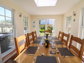 A dining room with a wooden table set with placemats, cutlery, glasses, a bottle, and a bowl at Towyn Hall in New Quay