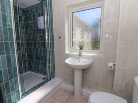 A bathroom with a shower, pedestal sink, frosted window with plant, and toilet at Towyn Hall in New Quay