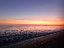 A beach during sunset with ocean waves at the shoreline