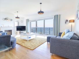 A living room with grey sofas a white coffee table a yellow rug a fireplace and large windows with sea view at Gwylanod in Llwyngwril near Fairbourne