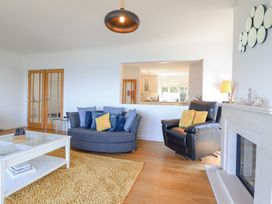 A living room with a blue sofa, black armchair, white coffee table, yellow rug, and fireplace at Gwylanod in Llwyngwril near Fairbourne