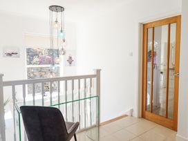 A hallway with a glass desk and chair near a wooden door with glass panels at Gwylanod in Llwyngwril near Fairbourne