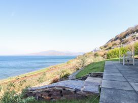 A patio with chairs overlooking the sea and hills at Gwylanod in Llwyngwril near Fairbourne