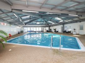 An indoor swimming pool with poolside furniture and plants at Tamar View Lodge Millbrook