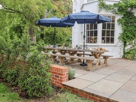 An outdoor dining area with a wooden table and umbrellas at Syleham House Syleham near Eye