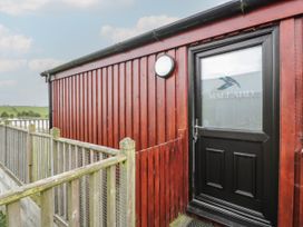 An exterior red wooden building with a black door labeled Mallard and a wooden railing surrounding a walkway at Mallard Lodge in Moscow near Galston