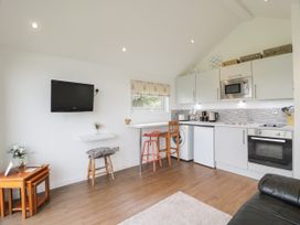 A small kitchen area with white cabinets a microwave oven sink washing machine and seating at Mallard Lodge in Moscow near Galston