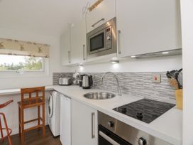 A kitchen with a sink stove microwave and wooden chairs near a window at Mallard Lodge in Moscow near Galston