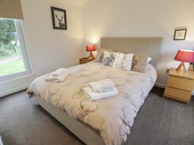 A bedroom with a bed with animal print bedding and cushions two bedside tables with red lamps and a window at Mallard Lodge in Moscow near Galston
