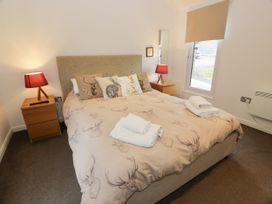 A bedroom with a bed with animal print duvet and pillows two wooden bedside tables with red lamps at Mallard Lodge in Moscow near Galston