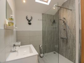 A bathroom with a sink a mirror a wall-mounted soap dispenser a glass-enclosed shower with a rain showerhead and handheld showerhead at Mallard Lodge in Moscow near Galston