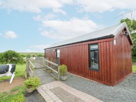 A wooden building with a deck and grassy area at Mallard Lodge in Moscow near Galston