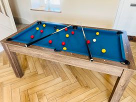 A pool table with balls and cue sticks in a game room at Rhos Las in Cerrigydrudion