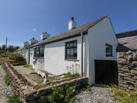 A cottage with a stone wall and garden at Bwthyn Y Swnt in Moelfre