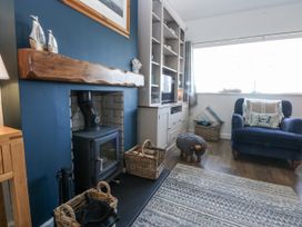 A living room with a fireplace and a blue chair at Bwthyn Y Swnt in Moelfre