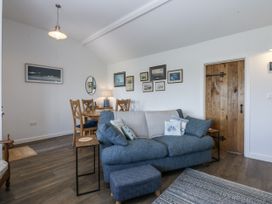 A living room with a sofa and dining table at Bwthyn Y Swnt in Moelfre