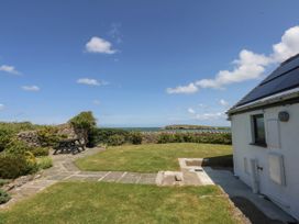 A garden with a table and sea view at Bwthyn Y Swnt in Moelfre