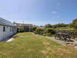 A garden with a picnic table and a paved path at Bwthyn Y Swnt in Moelfre