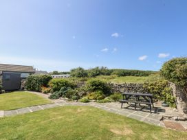 A garden with a stone patio and a bench at Bwthyn Y Swnt in Moelfre
