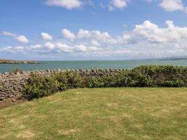 A garden with a stone wall and sea in the background at Bwthyn Y Swnt in Moelfre