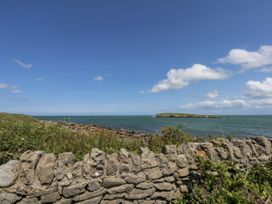 A coastal view with a stone wall and an island at Bwthyn Y Swnt in Moelfre
