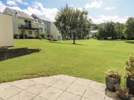 An outdoor area with grass and surrounding buildings at Bwthyn Y Swnt in Moelfre