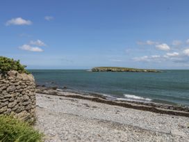 A beach view with an island in the distance at Bwthyn Y Swnt in Moelfre
