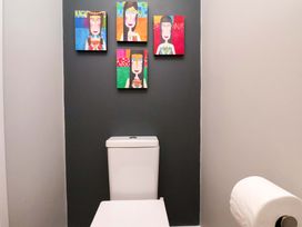 A bathroom with a toilet and artwork on the wall at The Beach Retreat The Bay - Filey
