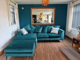 A living room with a teal sofa and mirror at Pasadena in Newquay