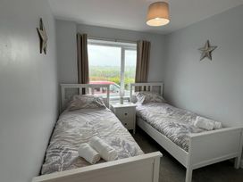 A bedroom with two single beds and a window at Llwyn Eithin in Benllech
