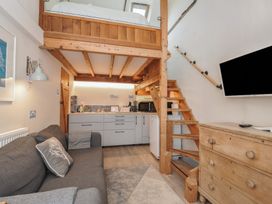 A living room with a kitchenette and staircase at Little Coombe in Trehunist near Liskeard